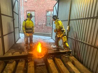To deltakere ved en glødende thermitsveis inne i treningsbåsen