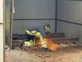Kursdeltaker arbeider med verktøy på skinnen med gnister fra kontaktpunktet