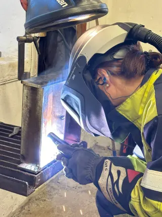 Nærbilde av sveiser med vernehjelm ved arbeidsbenken